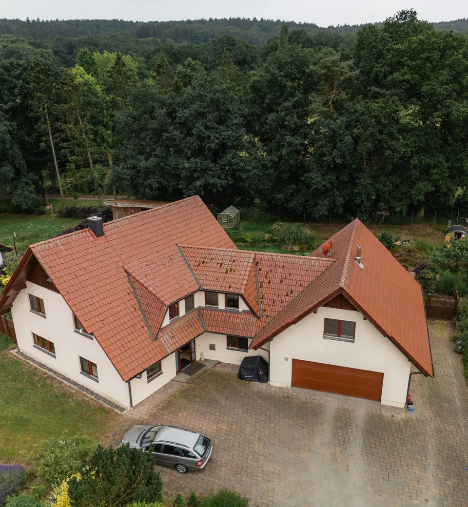Luftaufnahme des Wohnhauses mit Zufahrt, Garten und angrenzenden Bäumen